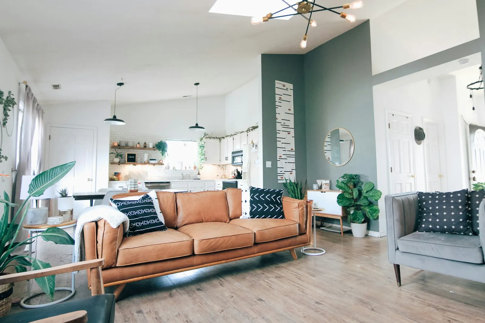 Tan leather sofa, houseplants and a patterned rug in a light-filled living room