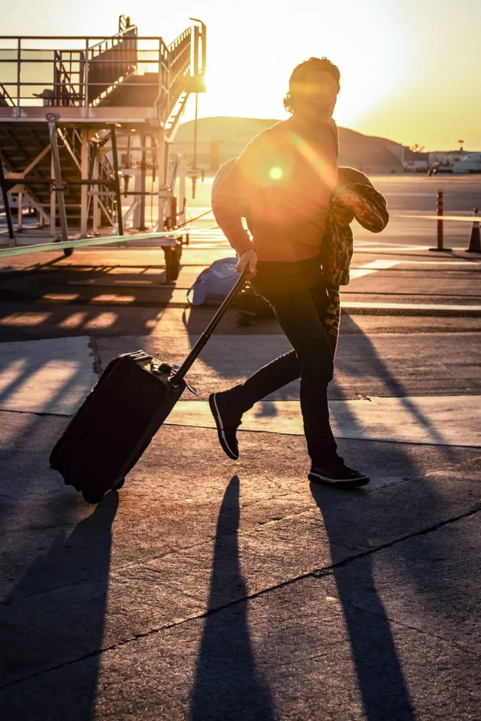 Traveller pulling a suitcase across an airport apron in warm evening light