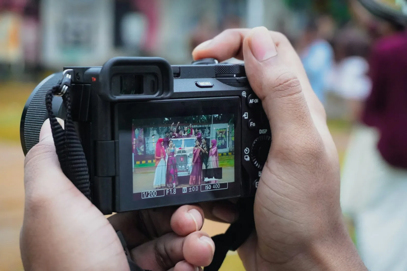 Hands holding a digital camera with a wedding scene on its rear screen
